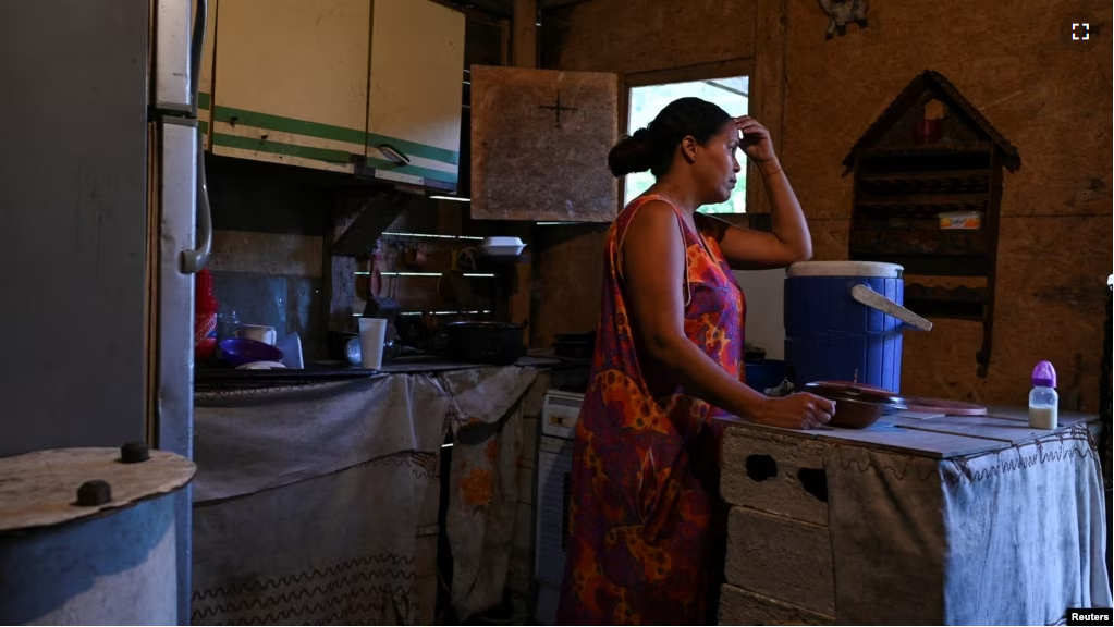 FILE - Gladys leans over a plastic containers that she fills daily with water through a community-made pipe system in the low-income neighborhood of Petare, in Caracas, Venezuela, May 12, 2023. (REUTERS/Gaby Oraa)