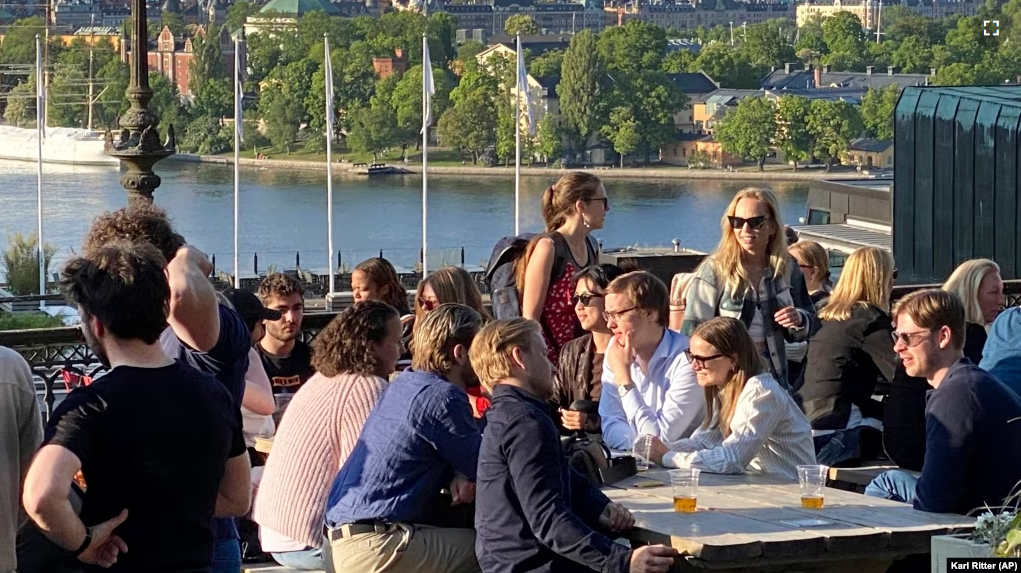 People enjoy drinks and snacks in the evening sun on a terrace overlooking Stockholm, on Tuesday, May 30, 2023. Smoking is prohibited in both indoor and outdoor areas of bars and restaurants in Sweden. (AP Photo/Karl Ritter)