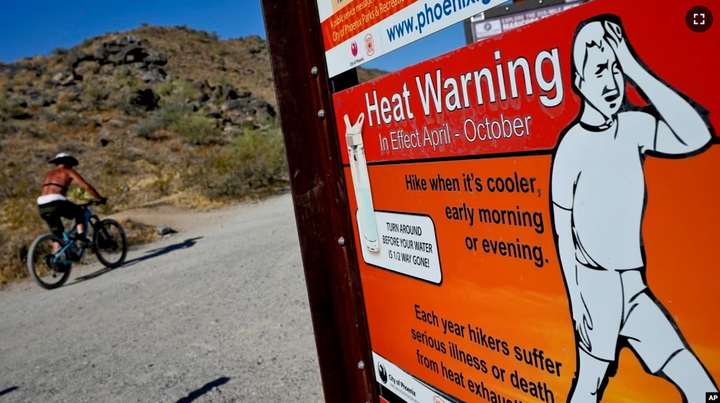 A cyclist finishes his ride early to beat high temperatures, Monday, July 10, 2023, in Phoenix. National Weather Service says Phoenix has had 10 consecutive days of 110 degrees or above. (AP Photo/Matt York)