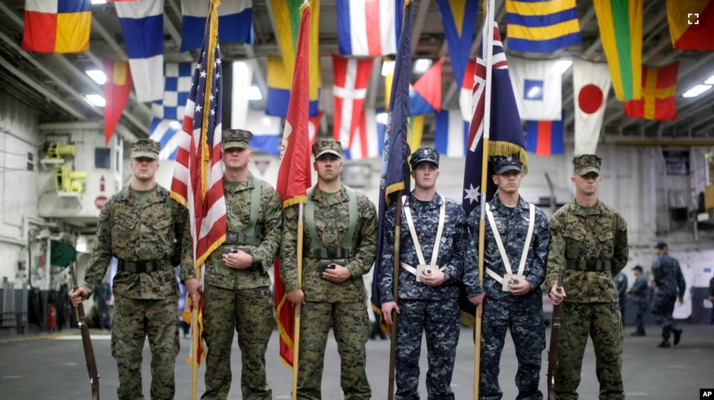 A flag party of U.S. Marines and Navy personnel take part in a ceremony marking the start of Talisman Saber 2017 aboard the USS Bonhomme Richard ship on the the Pacific Ocean off the coast of Sydney, June 29, 2017. (Jason Reed/Pool Photo via AP)