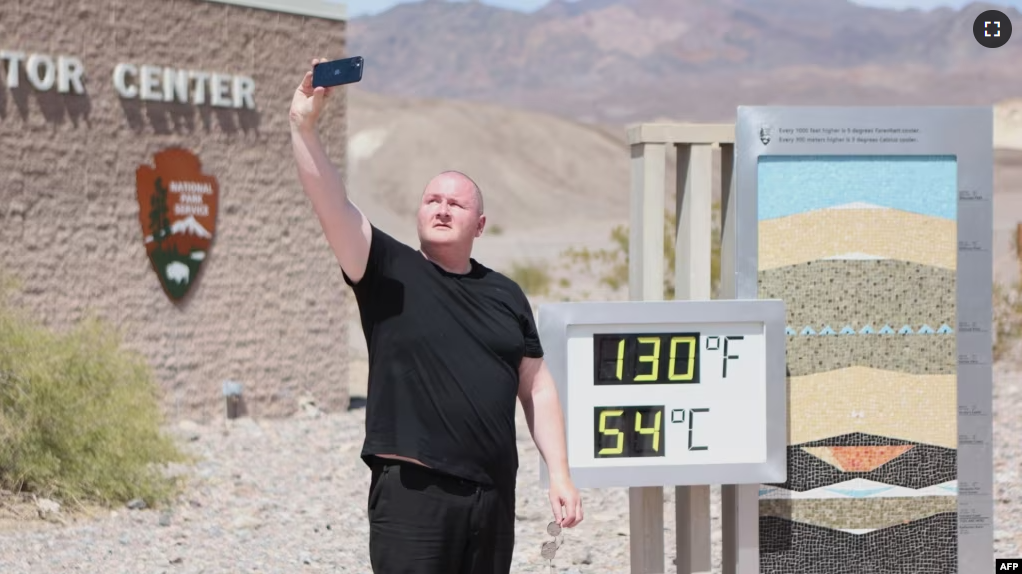 Scott Hughes, of Swansea, Wales, UK, takes a selfie next to a digital display of an unofficial heat reading at Furnace Creek Visitor Center during a heat wave in Death Valley National Park in Death Valley, California, on July 16, 2023. (Photo by Ronda Churchill / AFP)