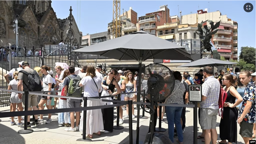 FILE - Tourist line up to enter at the Sagrada Familia basilica in Barcelona on July 18, 2023. (Photo by Pau BARRENA / AFP)