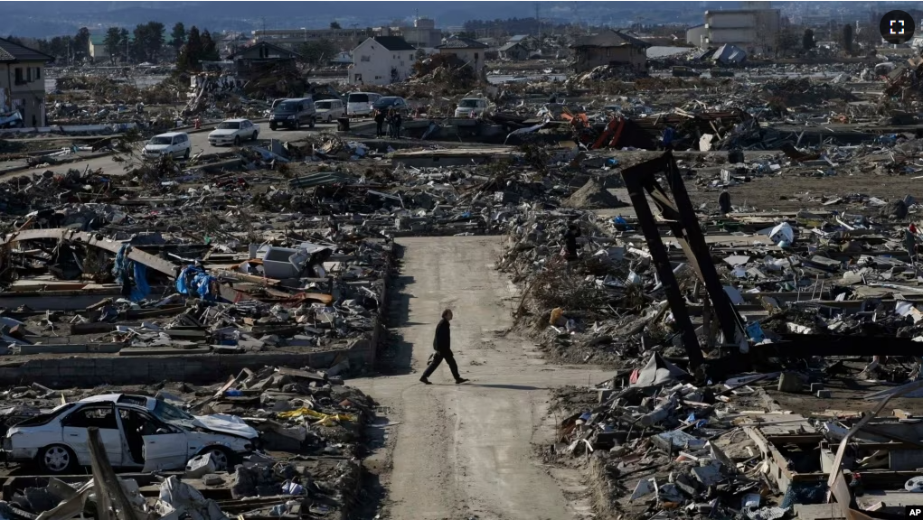 In this March 27, 2011 file photo, a man walks through an earthquake destroyed neighborhood below Weather Hill in Natori, Japan. (AP Photo/Wally Santana, File)