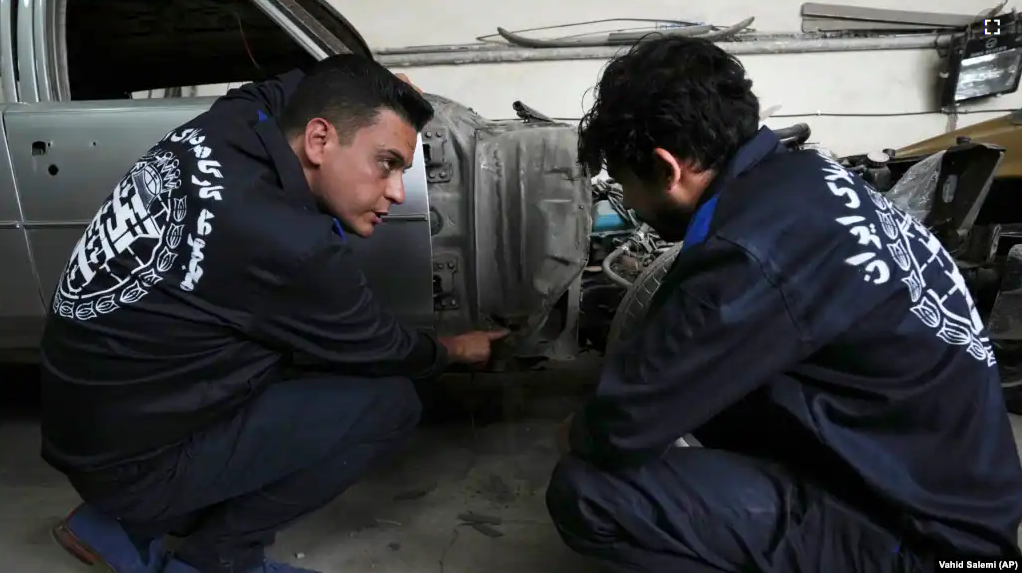 Khosro Dahaghin, left, talks with a worker at his workshop while restoring a Cadillac Seville, in Roudehen, some 30 miles (45 kilometers) east of downtown Tehran, Iran, Wednesday, June 7, 2023. (AP Photo/Vahid Salemi)