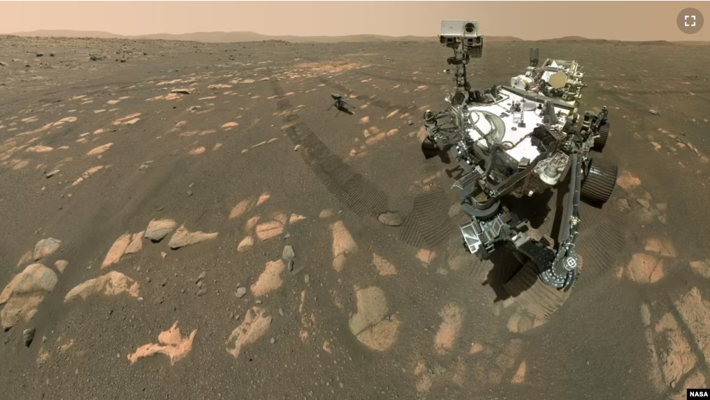 This April 6, 2021 image made available by NASA shows the Perseverance Mars rover, foreground, and the Ingenuity helicopter about 3.9 meters behind. This composite image was made by the WASTON camera on the rover's robotic arm. (NASA/JPL-Caltech/MSSS via AP)