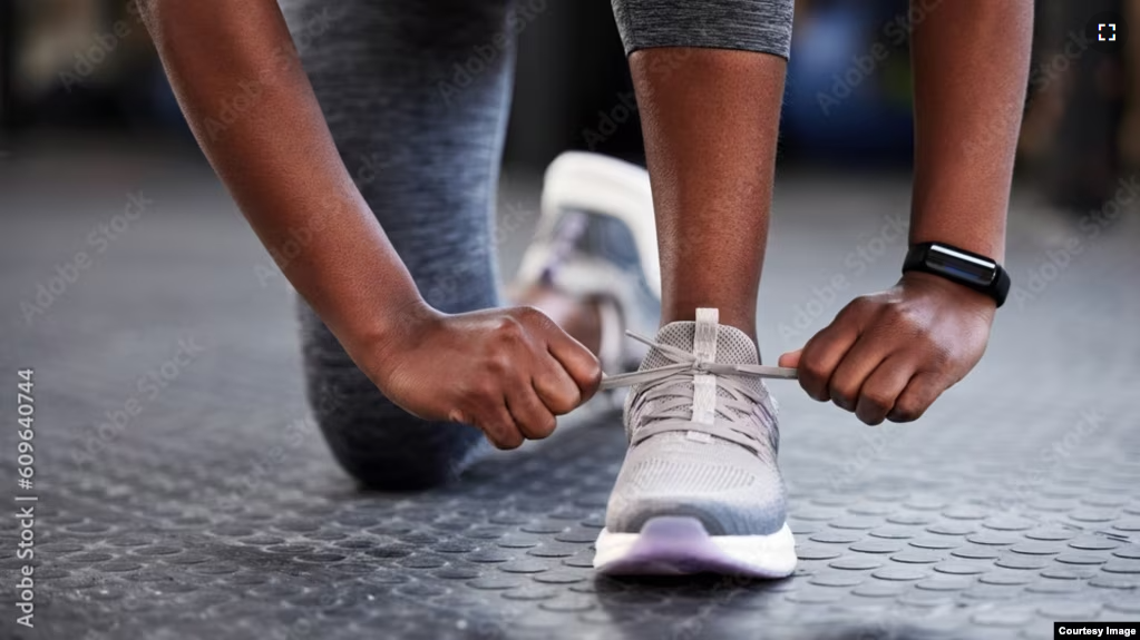 A woman ties up her shoestrings on her sneakers. (Adobe stock image)