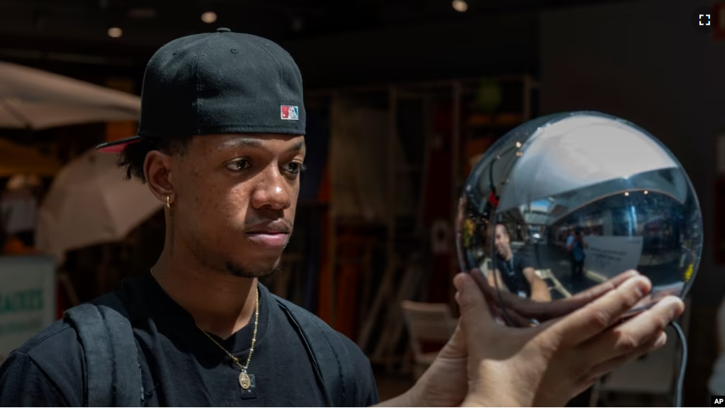 FILE - Carlos Jose, 21, has his eyes scanned by an orb, at a Worldcoin registration point in Barcelona, Spain, on Friday, Aug. 4, 2023. (AP Photo/Emilio Morenatti)