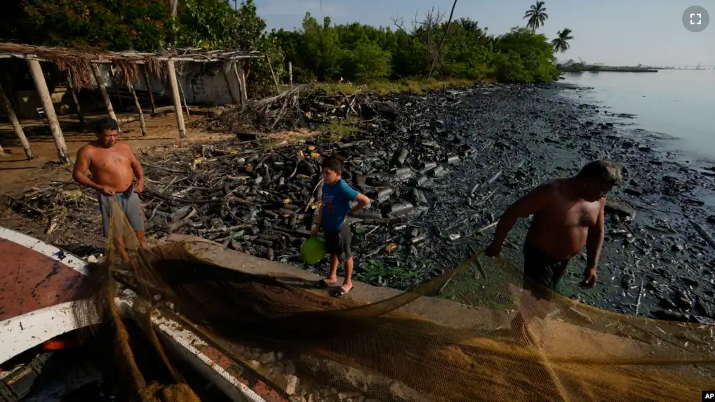 Fishermen spread out their net on the banks of Lake Maracaibo contaminated with oil and trash, in San Francisco, Venezuela, Wednesday, Aug. 9, 2023. (AP Photo/Ariana Cubillos)