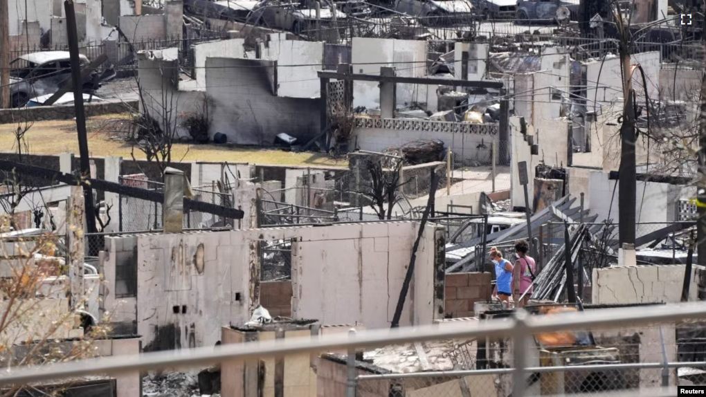 Two people examine a burned house after an inferno destroyed much of the historic Maui resort town of Lahaina, Hawaii, Aug. 13, 2023. (Sandy Hooper/USA Today Network via REUTERS)