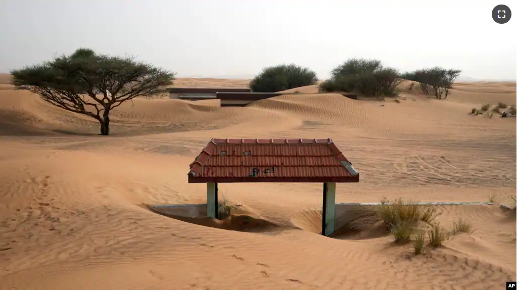 A house's entrance gate is buried under the sand at the Bedouin village of al-Ghuraifabout 100 km, 62 miles, southeast of Sharjah, United Arab Emirates, Sunday, July 9, 2023. (AP Photo/Kamran Jebreili)