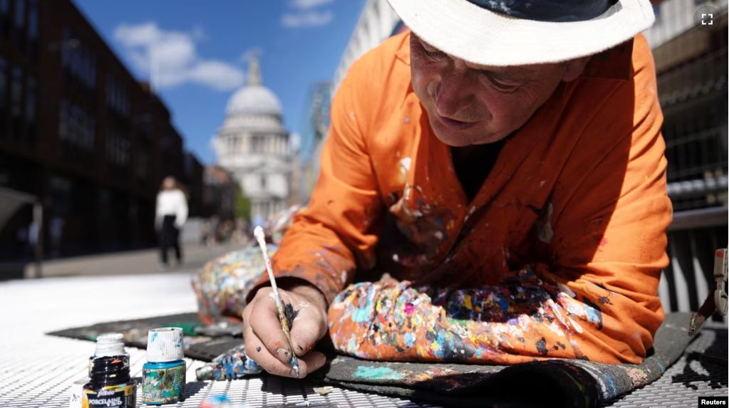 Ben Wilson, artist, paints on the Millennium Bridge, London, Britain, August 21, 2023. (REUTERS/Anna Gordon)