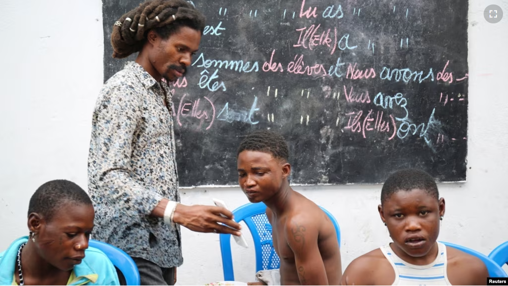 Cedrick Tshimbalanga, 32, the founder of Mokili Na Poche cultural centre, uses his phone while talking to homeless teenagers during a lunch at the cultural center in Kinshasa, Democratic Republic of Congo September 5, 2023. (REUTERS/Justin Makangara)