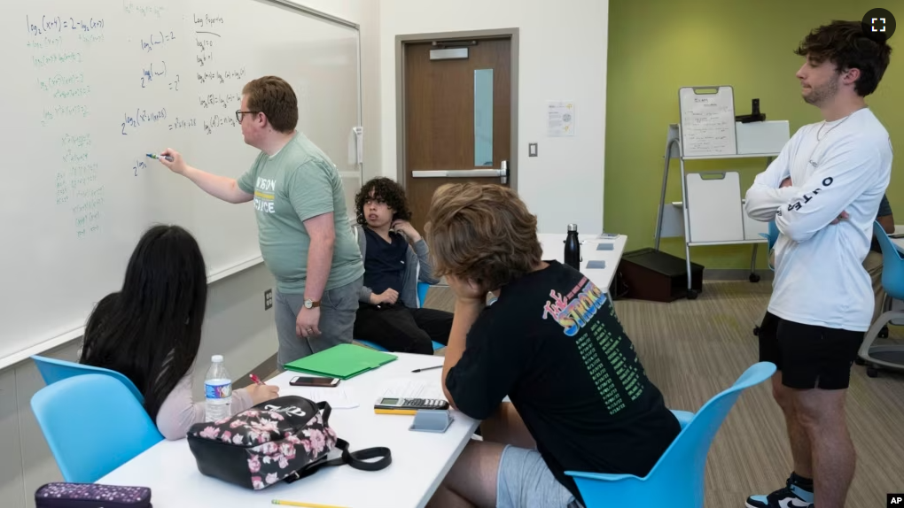 George Mason undergraduate math major David Wigginton writes an equation on a whiteboard as students Ethan Hill, right, and Diego Fonseca, center, take part in a summer math boot camp on Thursday, Aug. 1, 2023 at George Mason University in Fairfax. Va. (AP Photo/Kevin Wolf)