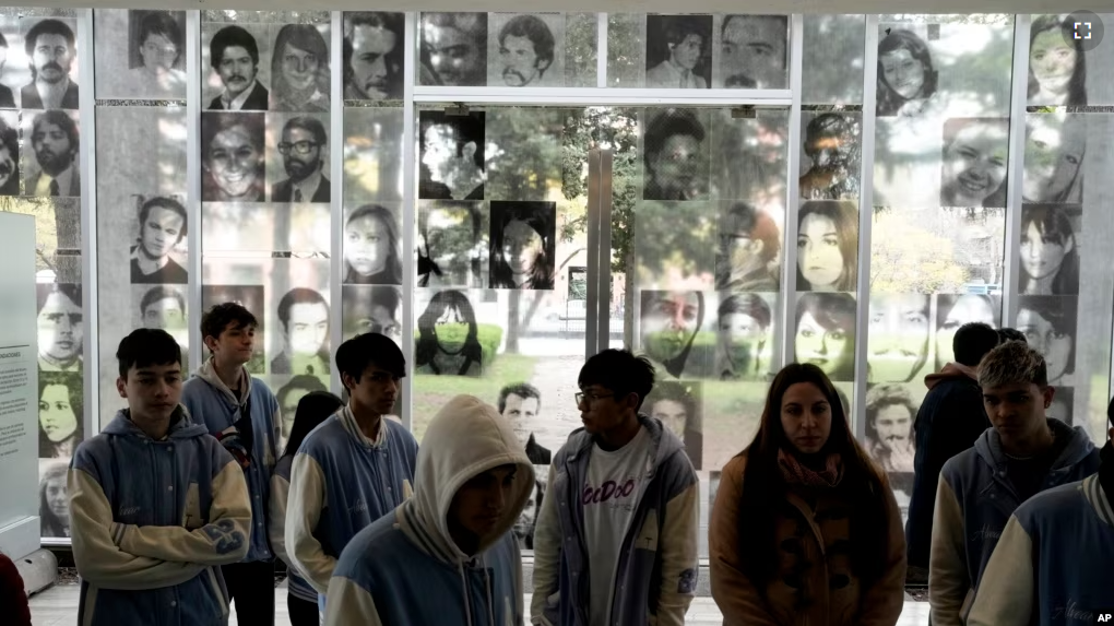 Photographs of people who disappeared during Argentina's dictatorship are displayed on the wall where students walk through the ESMA Museum and Site of Memory on Sept. 19, 2023. (AP Photo/Rodrigo Abd)