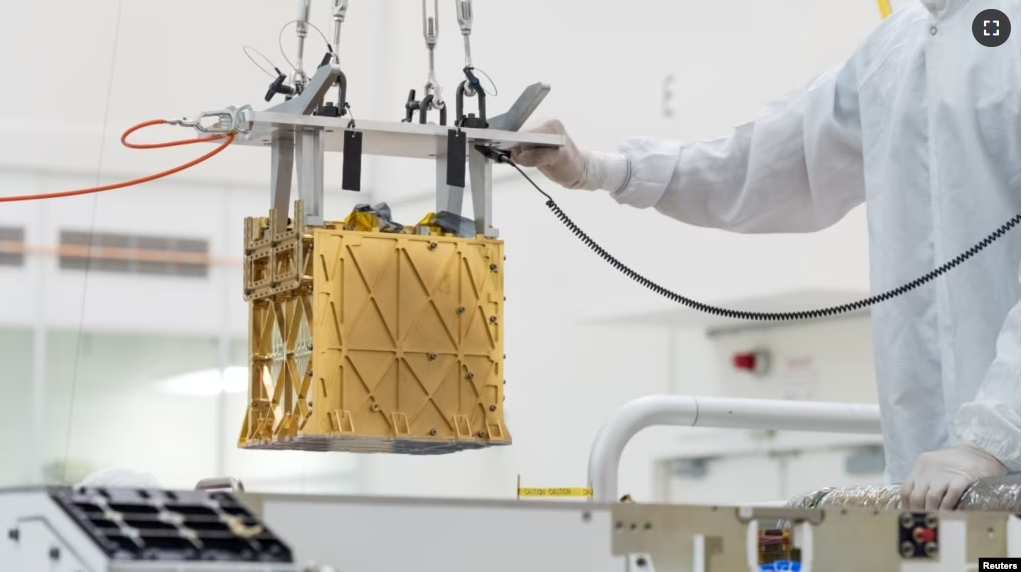 Technicians at NASA's Jet Propulsion Laboratory lower the MOXIE instrument into the belly of the Perseverance rover in an undated photograph in Pasadena, California. (NASA/JPL-Caltech/Handout via REUTERS)