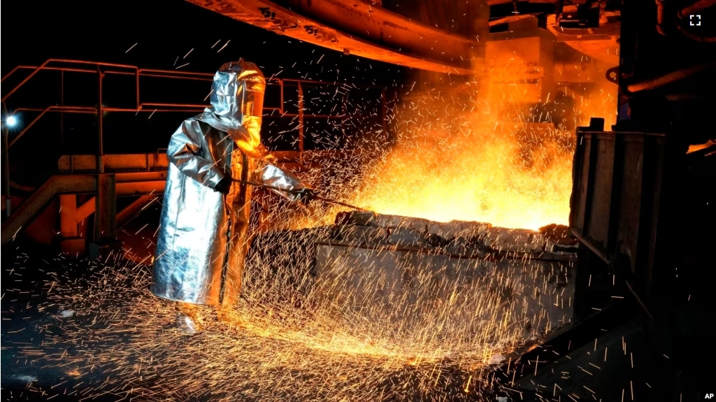 A worker in a protective suit pokes a metal rod to tap slag from a smelting furnace at PT Vale Indonesia's nickel processing plant in Sorowako, South Sulawesi, Indonesia, Tuesday, Sept. 12, 2023.