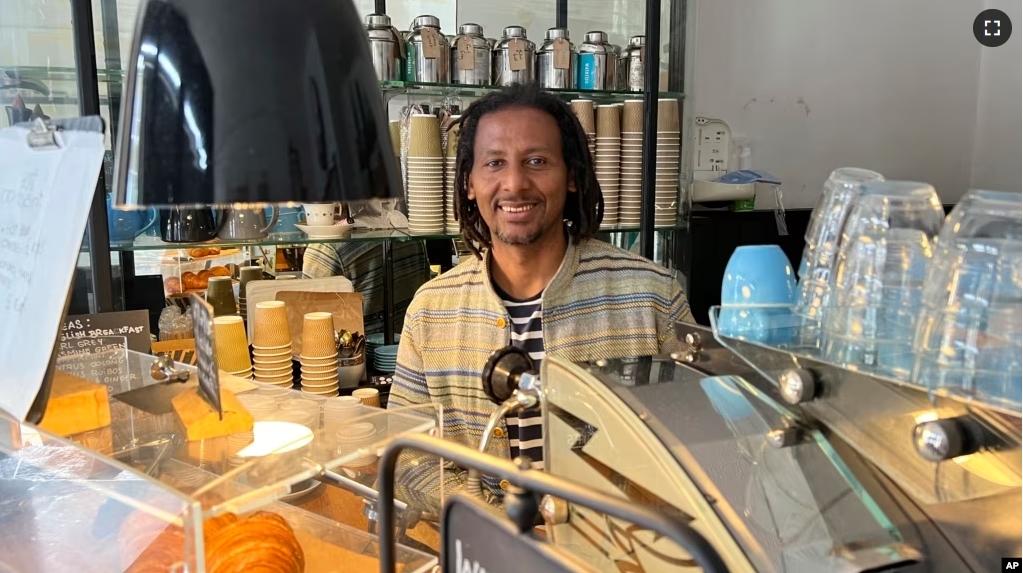 Anteneh Mulu, 46, poses behind the counter after serving a customer at his coffee shop, The Ethiopian Coffee Company, in central London on Thursday, Aug. 31, 2023. (AP Photo/Almaz Abedje)