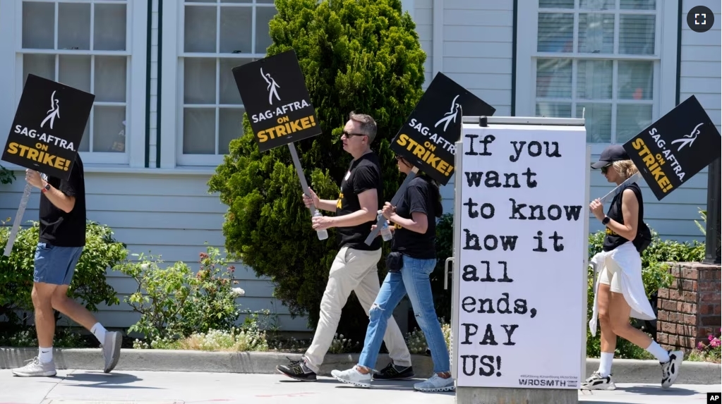 FILE - Picketers carry signs outside Amazon Studios in Culver City, Calif. on Monday, July 17, 2023. A tentative agreement between striking screenwriters and Hollywood studios offers some hope that the industry’s dual strikes may be over soon. (AP Photo/Chris Pizzello, File)