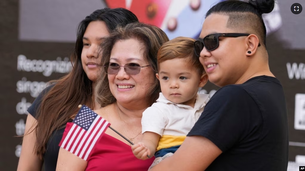 FILE - Rita Guevara of the Philippines, center, takes a photo with her family following a naturalization ceremony, Sept. 15, 2023, in Miami. (AP Photo/Marta Lavandier)