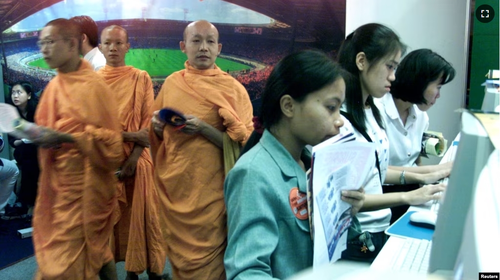 FILE - Thai Buddhist Monks walk past a line of internet users at an internet expo on May 25, 2000. (REUTERS/File photo)