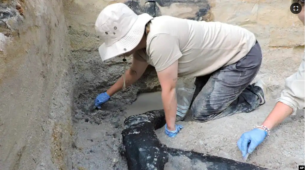 In this photo provided by researchers, an excavation team uncovers a wooden structure found on a riverbed near a waterfall in Zambia in 2019. (Larry Barham/University of Liverpool via AP)