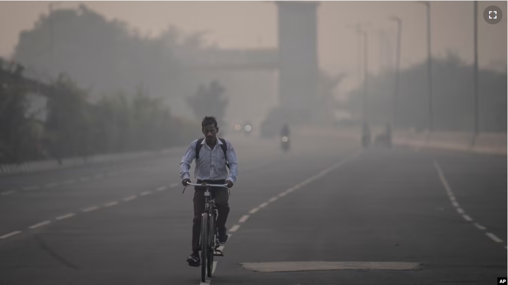 A cyclist rides amid smog in New Delhi, India, Tuesday, Nov. 7, 2023. Masks are back on the streets as residents of the capital city grapple with the annual surge in air pollution that has engulfed the region. (AP Photo/Altaf Qadri)