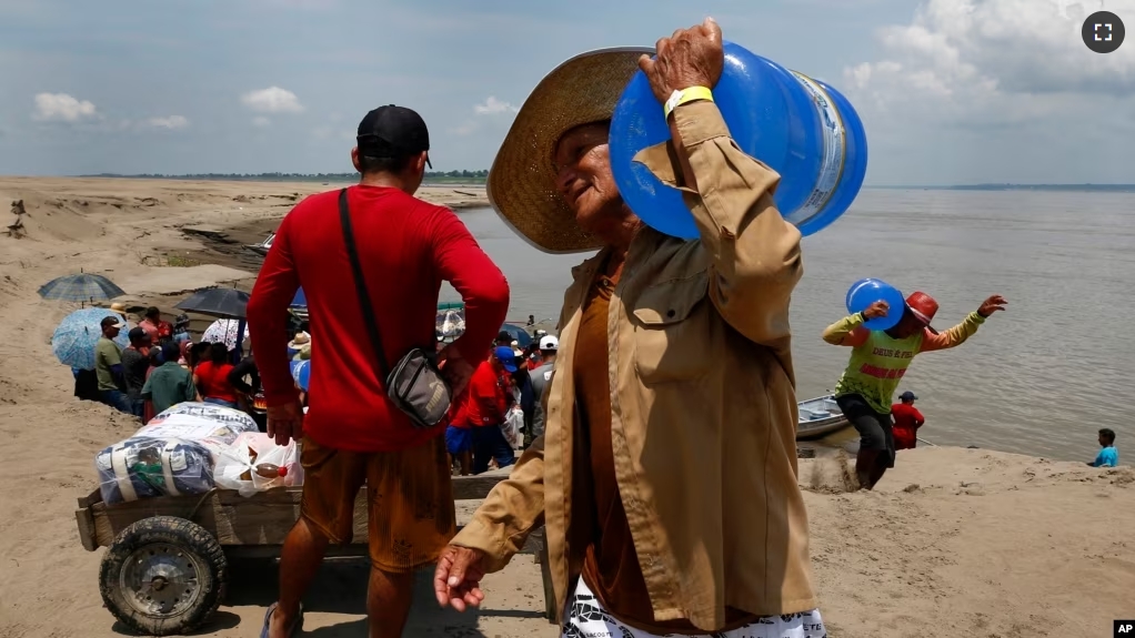 A resident of a riverside community carries a container of drinking water from an aid distribution due to the ongoing drought in Careiro da Varzea, Amazonas state, Brazil on October 24, 2023.(AP Photo/Edmar Barros)