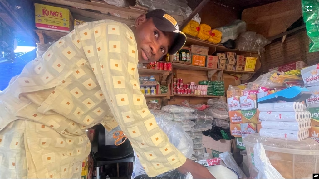 Abba Usman sells granulated sugar at his shop inside a market in Abuja, Nigeria on Oct. 27, 2023. The same 50-kilogram bag of sugar that Usman bought a week ago for $66 now costs $81. As prices rise, his customers are dwindling. (AP Photo/Chinedu Asadu)