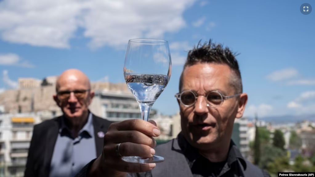 Mineral water sommelier Martin Riese, right, examines a glass of fine water during an International Water Tasting Competition, in Athens, Greece, on Wednesday, April 26, 2023, accompanied by Michael Mascha, founder of the Fine Water Society. (AP Photo/Petros Giannakouris)