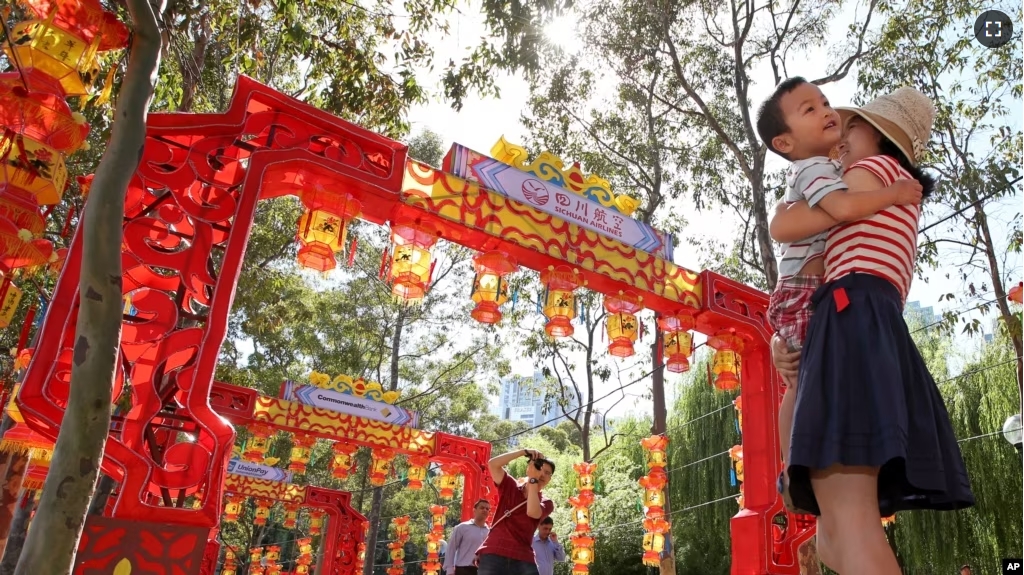 FILE - Pen Pu (center) and Chelsea Peng play with their three-year-old son Dore Peng at the Chinese Garden of Friendship in Sydney, Australia, 2015. (AP Photo/Rick Rycroft)