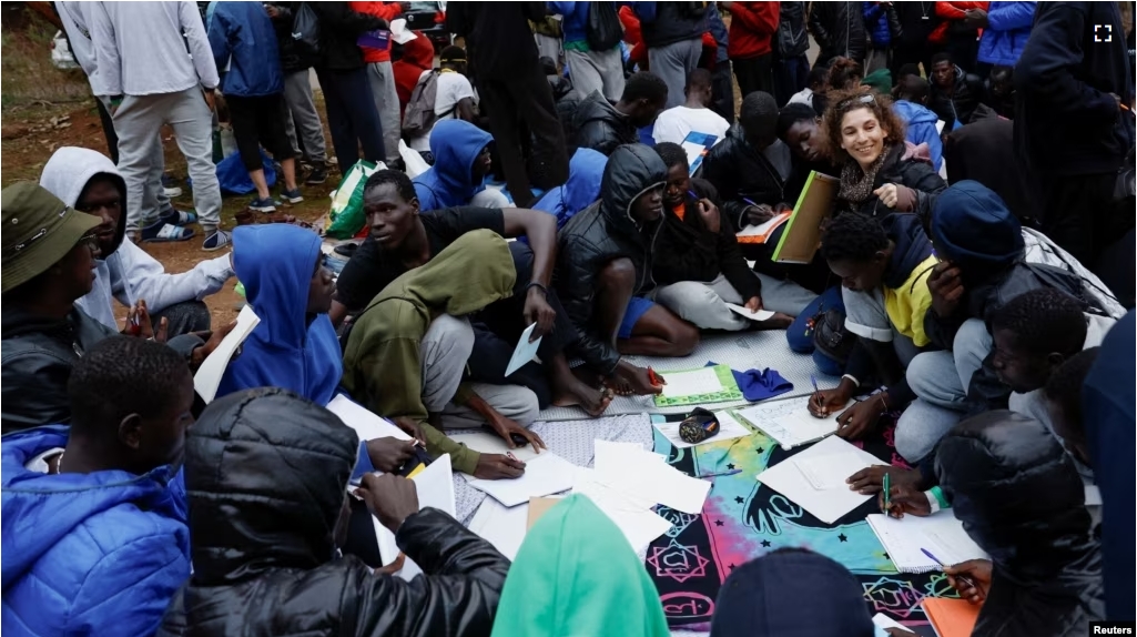 Several volunteers give Spanish classes to migrants outside the Las Raices Camp in La Laguna, Spain, November 5, 2023. (REUTERS/Borja Suarez)