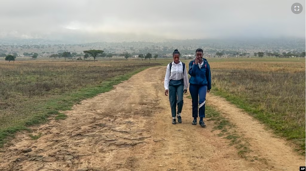 Luyanda Hlali, left, and her friend Mimi Dubazane embark on their routine 2 hour-long walk from the village of Stratford to their school in Dundee, South Africa, Thursday, Oct. 26, 2023. (AP Photo/ Mogomotsi Magome)