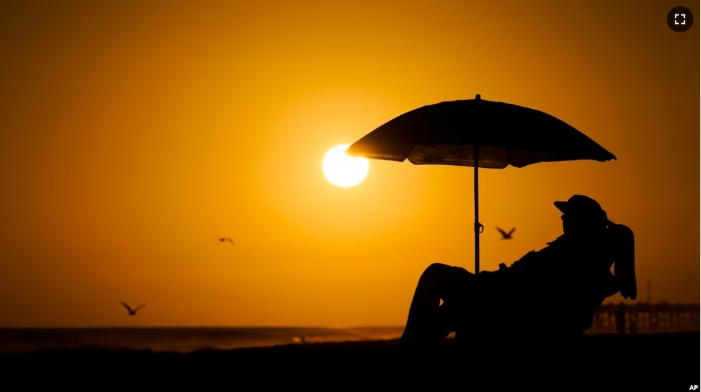 FILE - A person rests under an umbrella as the sun sets, Sept. 12, 2023, in Newport Beach, Calif. European Union scientists said 2023 would be the warmest year on record. (AP Photo/Ryan Sun, File)