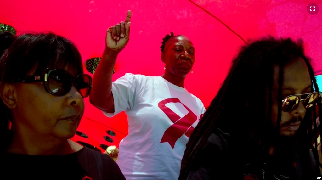 FILE - A woman dances as she listens to music while attending a World AIDS Day commemoration at Nkosi's Haven in Johannesburg on Nov. 30, 2019 on the eve of World AIDS Day. (AP Photo/Denis Farrell, File)