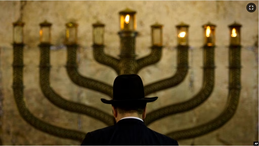 FILE - An Ultra-Orthodox Jewish man stands in front of a menorah on the third eve of Hanukkah, at the Western Wall, Judaism's holiest site in Jerusalem's old city on December 13, 2009. (AP Photo/Sebastian Scheiner, File)