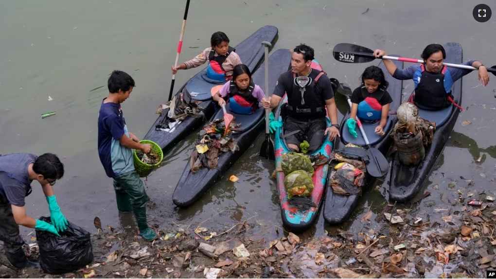 Environmental activist members of the Situ Gede Cleanliness Warrior pick up trash while paddling kayaks at Setu Gede lake in Bogor, West Java, Indonesia, Tuesday, Oct. 10, 2023. (AP Photo/Achmad Ibrahim)