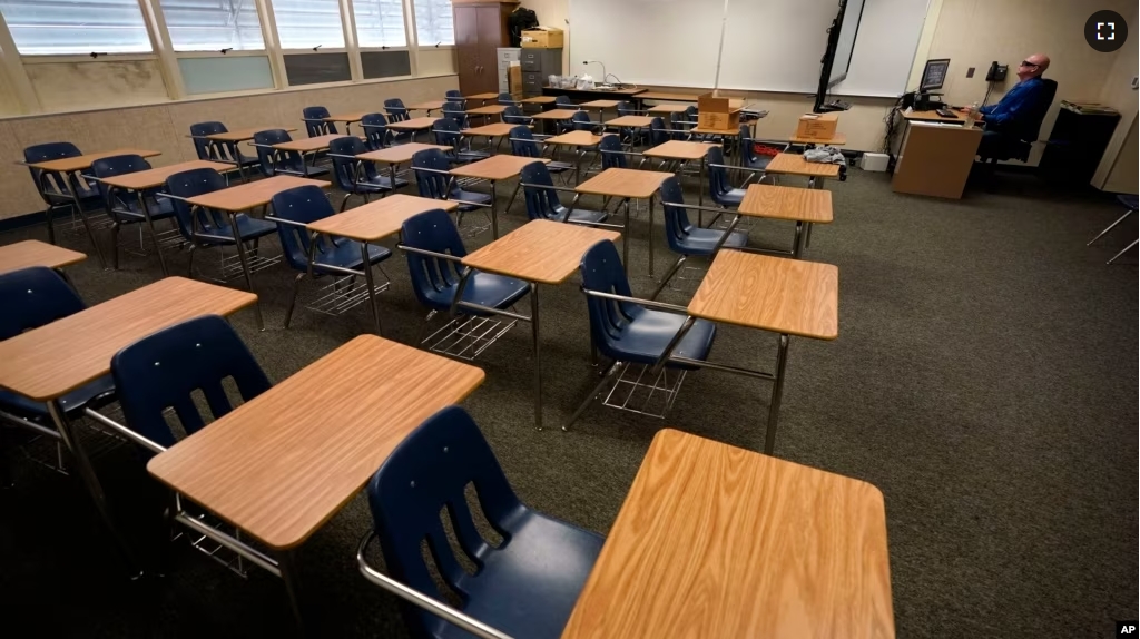 FILE - Math teacher Doug Walters sits among empty desks as he takes part in a video conference with other teachers to prepare for at-home learning at Twentynine Palms Junior High School in Twentynine Palms, Calif., Aug. 18, 2020. (AP Photo/Gregory Bull, File)