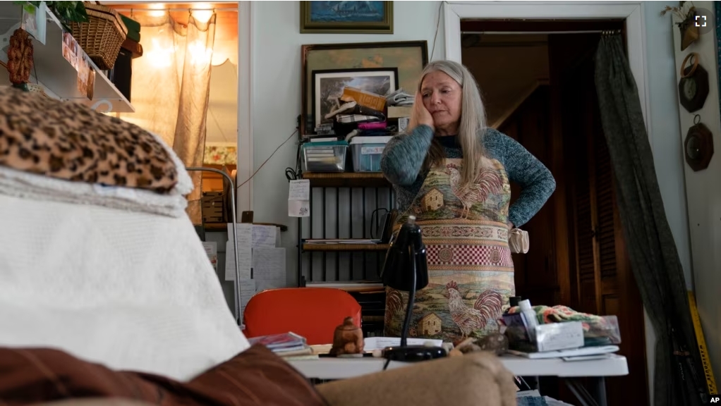 FILE - Nancy Rose, who contracted COVID-19 in 2021 and exhibits long-haul symptoms including brain fog and memory difficulties, pauses while organizing her desk space, Jan. 25, 2022, in Port Jefferson, New York. (AP Photo/John Minchillo, File)