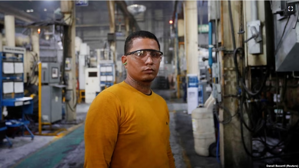 Walter Banegas, 28, originally from Honduras, poses for a picture during his shift at the Pace Industries aluminum injection molding plant, his formal job after settling in Mexico as a refugee, in Saltillo, Mexico October 16, 2023. (REUTERS/Daniel Becerril)