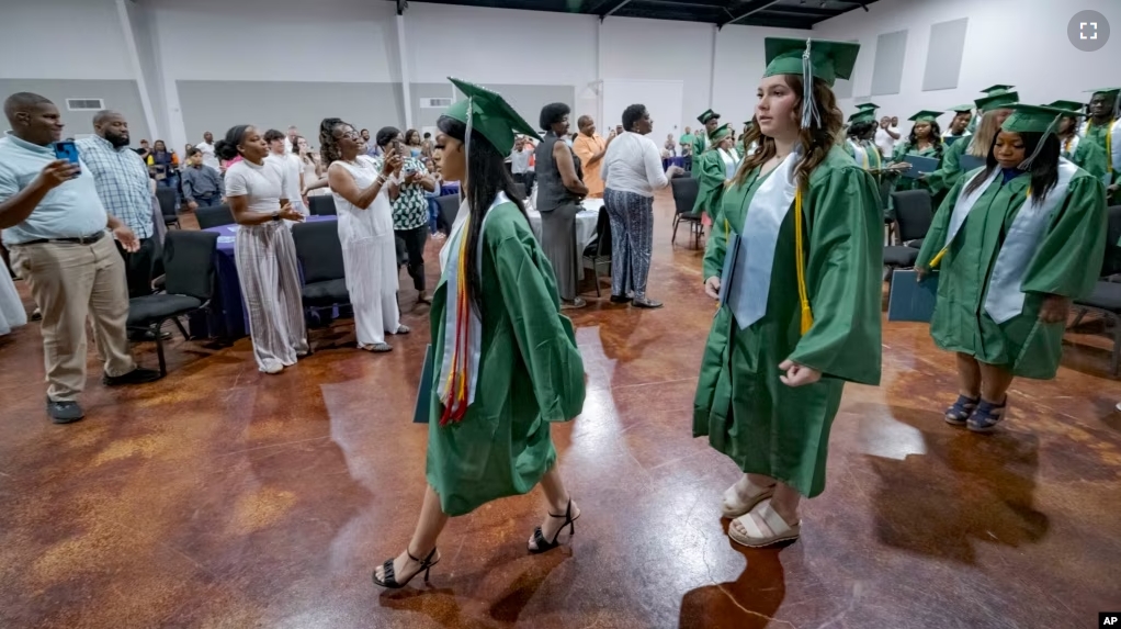 Salutatorian Alasia Baker, 17, center, and Khyli Barbee, 15, following Baker, leave a graduation ceremony for Springfield Preparatory School at Victory in Christ church in Holden, La., Saturday, Aug. 5, 2023. (AP Photo/Matthew Hinton)