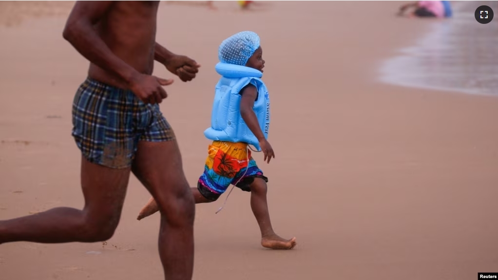 FILE - A child runs as beach-goers enjoy New Year's Day in the rain, on the beach in Durban, South Africa January 1, 2024. (REUTERS/Rogan Ward)