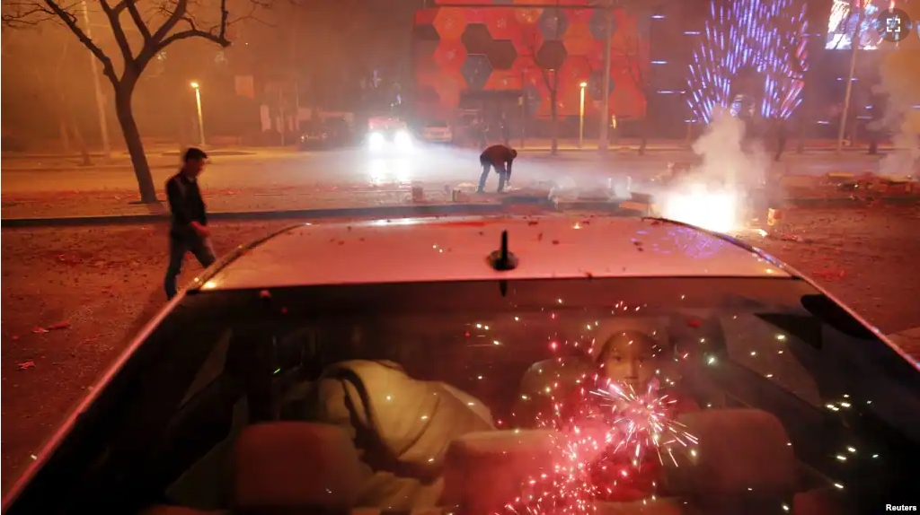 FILE - A girl sits inside the car as firecrackers and fireworks explode celebrating the start of the Chinese Lunar New Year in Beijing just before midnight February 7, 2016. (REUTERS/Damir Sagolj)