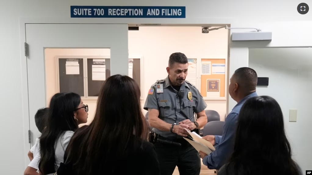 An officer listens to a question as he directs people to a courtroom, Wednesday, Jan. 10, 2024, in an immigration court in Miami. (AP Photo/Wilfredo Lee)