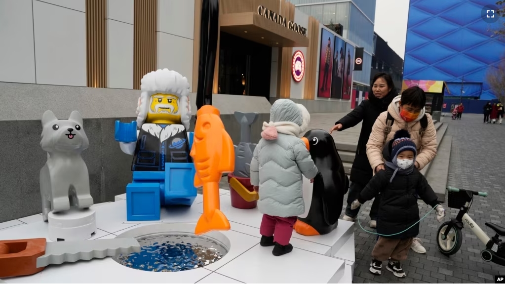 Children play near a display depicting an elderly person at a shopping mall in Beijing, Wednesday, Jan. 17, 2024. China's population dropped by 2 million people in 2023, the government recently. (AP Photo/Ng Han Guan). (AP Photo/Ng Han Guan)