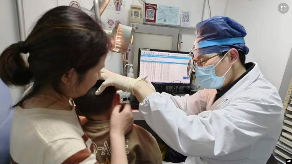 In this photo provided by researchers in January 2024, Dr. Yilai Shu examines a young patient at the Eye & ENT Hospital of Fudan University in Shanghai, China, after a gene therapy procedure for hereditary deafness. (Courtesy Dr. Yilai Shu via AP)