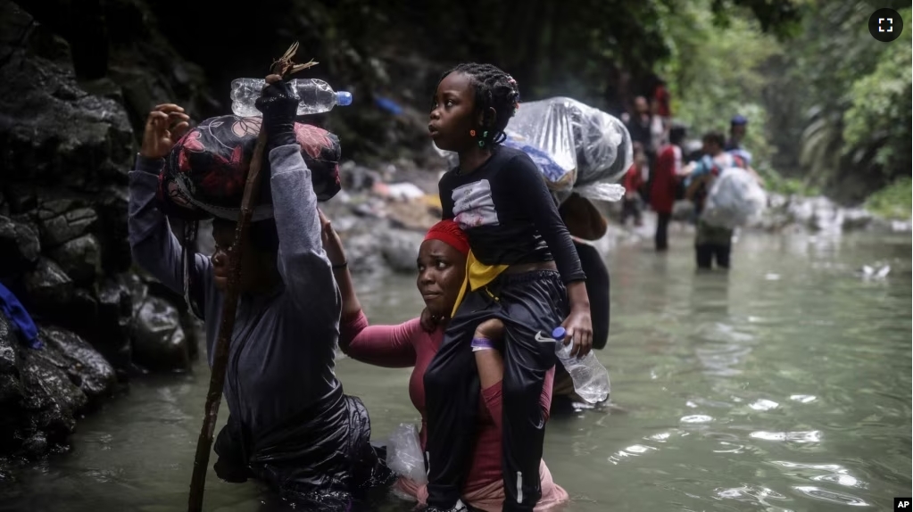 FILE - Haitian migrants wade through a river as they cross the Darien Gap from Colombia to Panama in hopes of reaching the United States, May 9, 2023. (AP Photo/Ivan Valencia)