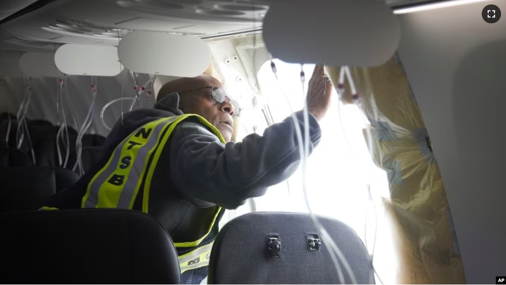 Investigator-in-Charge John Lovell examines the fuselage plug area of Alaska Airlines Flight 1282 on Sunday, Jan. 7, 2024, in Portland, Oregon. (National Transportation Safety Board via AP)