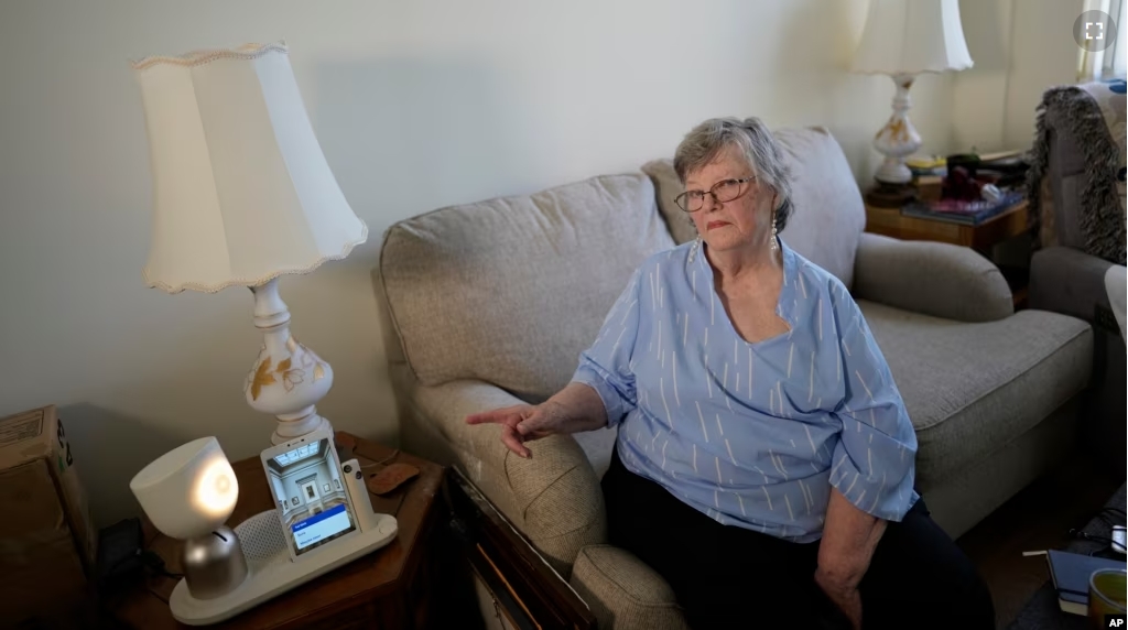 Joyce Loazia interacts with ElliQ, left, a tabletop device that uses artificial intelligence to conduct human-like conversations, during an interview in her apartment in a senior community in Coral Springs, Florida, on December 5, 2023. (AP Photo/Rebecca Blackwell)