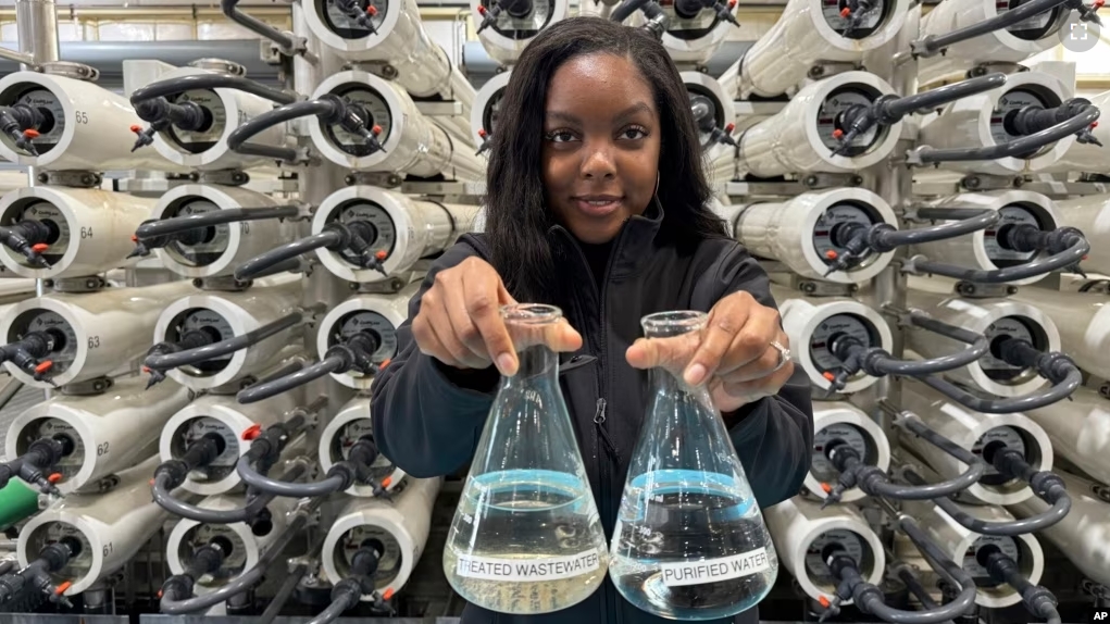 Lakeisha Bryant, public information representative at the Santa Clara Valley Water District, holds flasks of water before and after it is purified at the Silicon Valley Advance Purification Center on December 13, 2023, in San Jose, California. (AP Photo/Terry Chea)