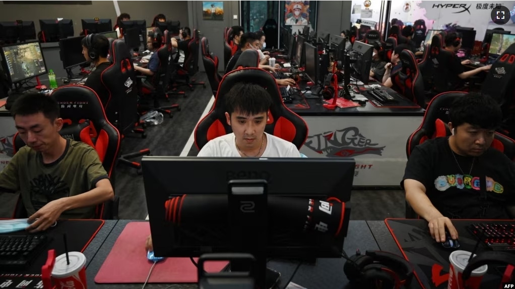 FILE - People play computer games at an internet cafe in Beijing on September 10, 2021. China recently announced new plans to restrict the online gaming industry, sending shares in tech giants including Tencent tumbling. (Photo by GREG BAKER / AFP)